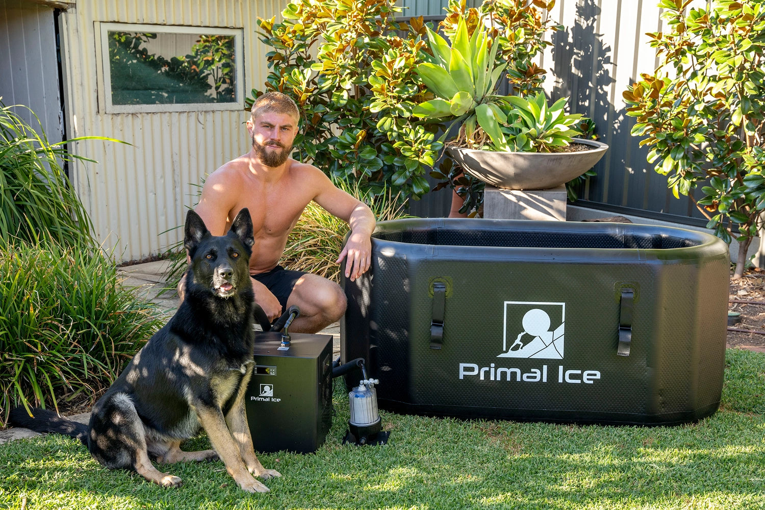 Man with German Shepherd beside Primal Ice tub chiller and filtration system in backyard