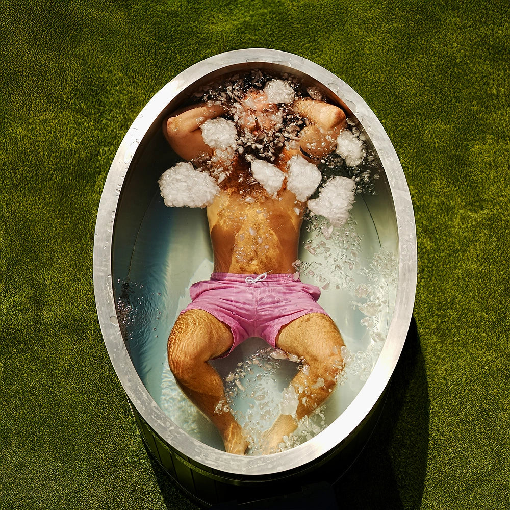 Top view of man fully submerged in ice bath with ice cubes around head and shoulders