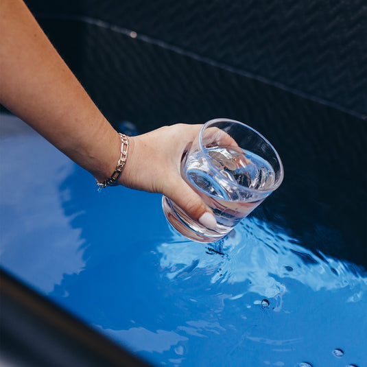 person filling a glass with water from an ice bath